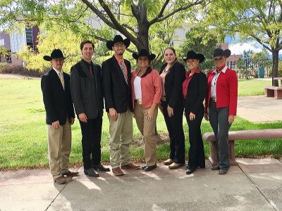 6 team members and coach pose in a line outside for group photo.