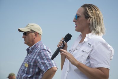 Woman in field speaks into microphone.