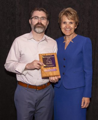 Man and woman stand with plaque