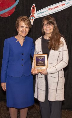 Two women stand holding plaque