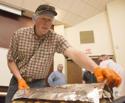 Student puts plate of lamb burgers on counter