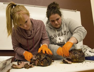 Two students cut pieces of meat