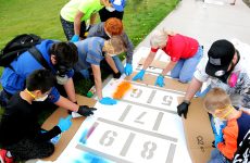 A group gathers around the hopscotch stencil.