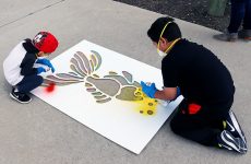 Two boys paint the fish stencil