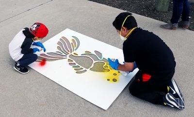 Two boys paint the fish stencil