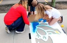A family paints the frog stencil.