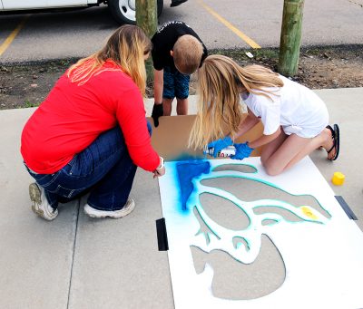 A family paints the frog stencil.