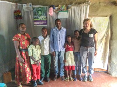 3 adults and 4 children standing in a row in a house in Africa.