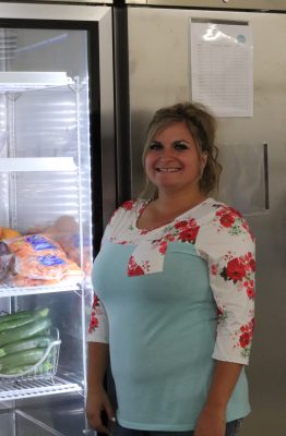 Sierra Mitchell stand besides the food pantry refrigerators