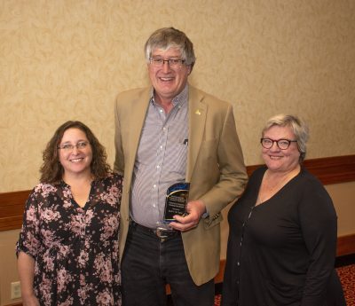 Photograph of three people with award