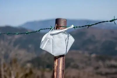 blue paper mask hanging on barb wire fence