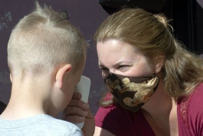 Woman takes forehead temperature of young boy