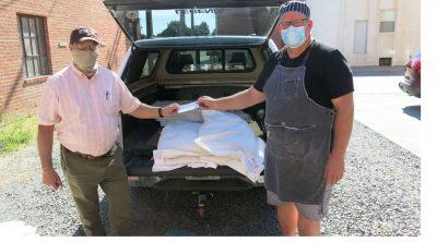 Two people shown in front of a sack of grain handing over a check.