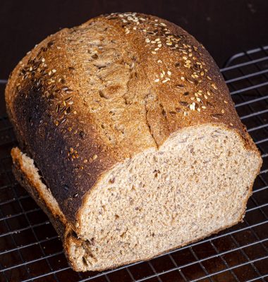 loaf of whole wheat bread with sesame and flax seeds sprinkled on top.