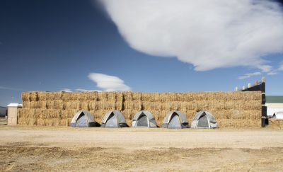 Tents are in front of large bales