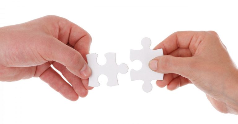Hands putting two puzzle pieces together