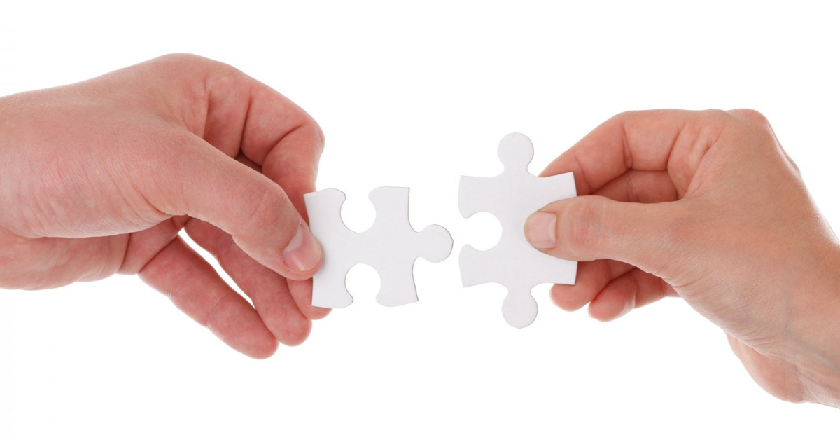 Hands putting two puzzle pieces together