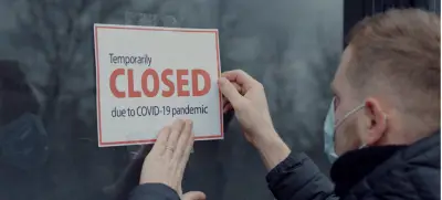 Individual hanging Closed sign on business