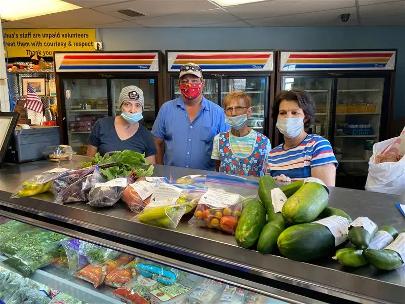 Four individuals standing behind produce fridge