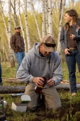 Man kneeling in dirt testing soil pH
