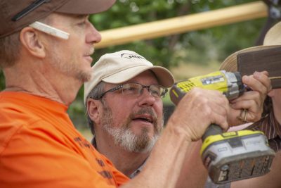 Two people secure plastic sheathing