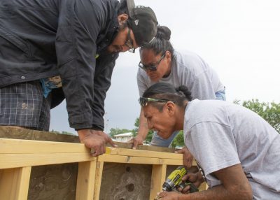 three people attaching wood pieces together