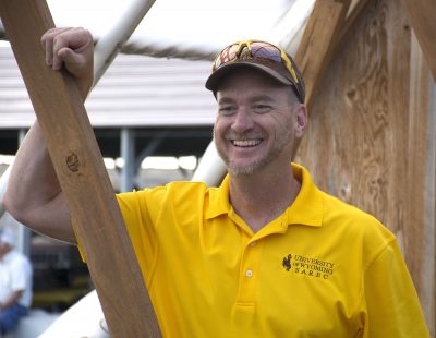 Man standing in UW Extension shirt, hat