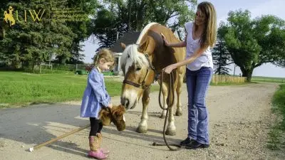Little girl in pigtails showing Pistol her stick horse.
