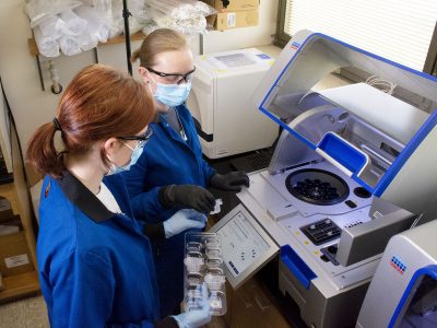 Two laboratory workers in front of machine