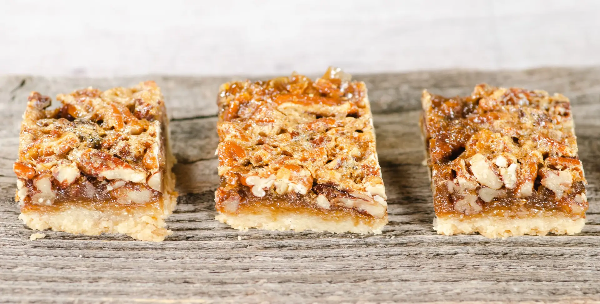 3 pecan bar cookies on wood plank