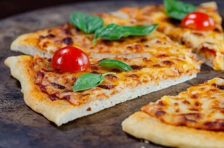 thin crust cheese pizza topped with fresh basil and cherry tomatoes