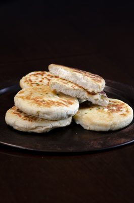 small round breads with chopped garlic on metal plate