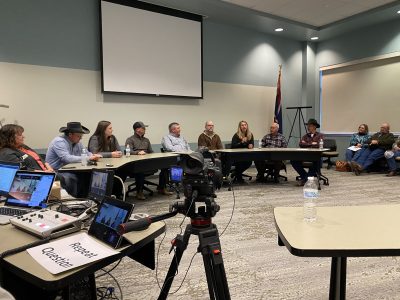 Panel presentation with 8 people sitting in front of a classroom.