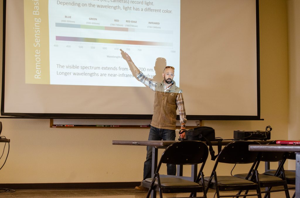 man pointing at Powerpoint slide on a projection screen.