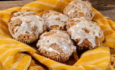 5 streusel topped muffins with vanilla icing drizzle in a yellow towel