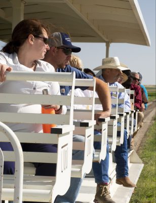 People sit on white metal benches in a wagon with white metal roof