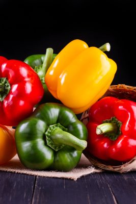 red, yellow, and green bell peppers on a wood table