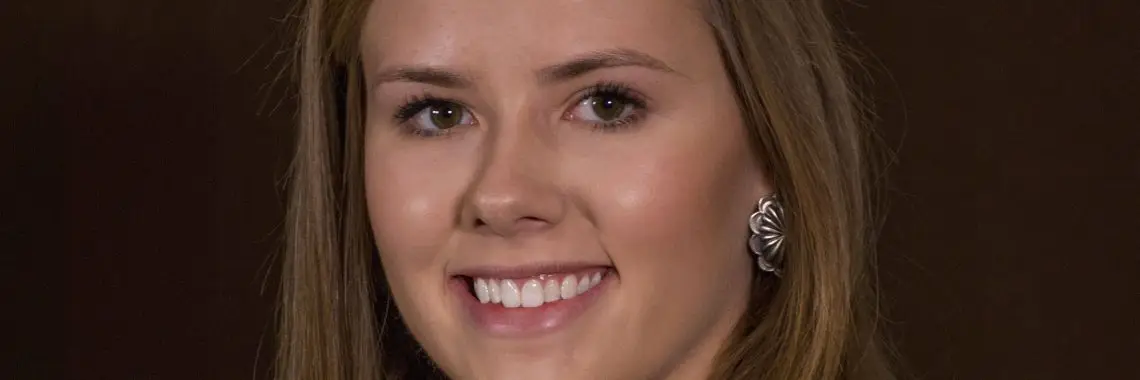 headshot of smiling woman wearing black shirt and yellow jacket