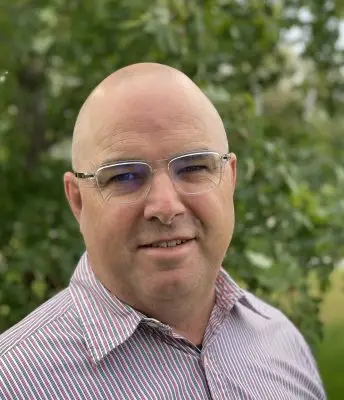 smiling bald man wearing glasses and striped shirt