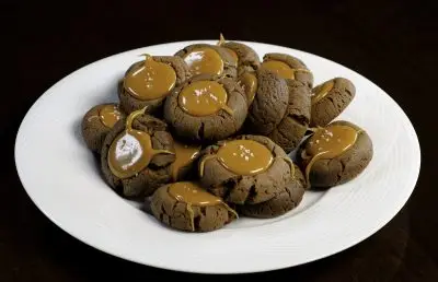 plate of chocolate thumbprint cookies with caramel centers sprinkled with a few grains of salt