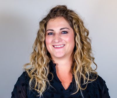 smiling woman with curly blonde hair and black shirt