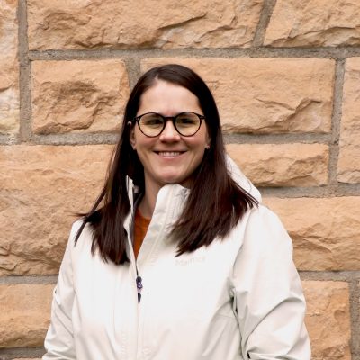 portrait of smiling woman with brown hair and glasses wearing white rain jacket