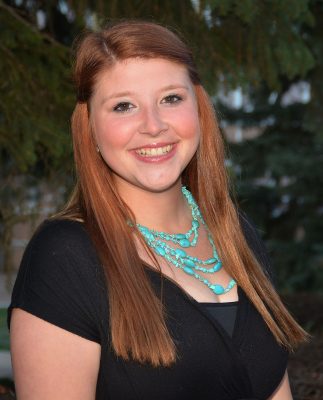 Portrait of smiling red-headed woman wearing turquoise necklace and black shirt