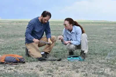 man wearing blue shirt and holding paper and pencil confers with woman wearing sunglasses and holding a mountain plover