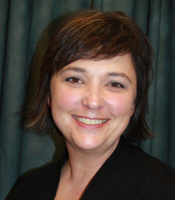 head shot of a smiling woman with brown eyes and short dark hair, wearing black shirt