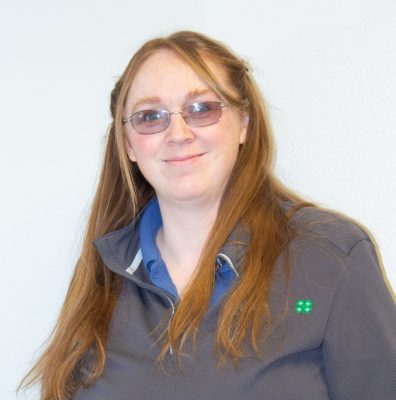 portrait of smiling woman with red hair and glasses wearing gray pullover with green 4-H logo