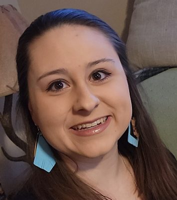 Smiling woman with dark hair wearing dangly turquoise earrings