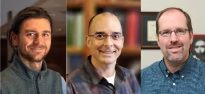 headshots of three smiling men. The leftmost has brown hair in a ponytail and is wearing a gray vest and the two others are wearing glasses and plaid button down shirts.
