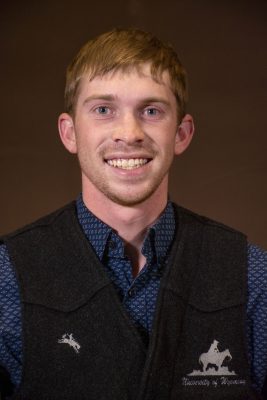 smiling man wearing charcoal-colored wool vest over blue collared shirt with paisley print