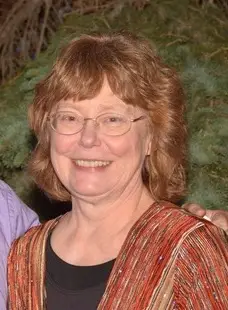 smiling woman with reddish hair and glasses wearing red jacket over black shirt
